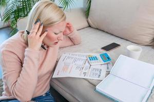 Beautiful young Albino woman sitting with calculator and bills, doing paperwork. Hand woman doing finances and calculate on desk about cost at home office.Concept work from home photo