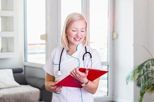 Doctor woman filling up medication history record while standing in her office . Physician at work, portrait shoot. Medicine and health care concept photo