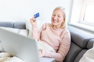 Young Woman On Sofa Shopping Online With Debit Card. Beautiful girl using laptop computer for online shopping at home photo