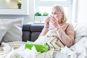 Sick Albino Woman.Flu.Woman Caught Cold. Sneezing into Tissue. Headache. Virus .Medicines. Young Woman Infected With Cold Blowing Her Nose In Handkerchief. Sick woman with a headache sitting on a sofa photo