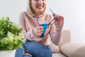 Woman cleaning reading glasses with cloth. Women hand cleaning glasses lens with blue cloth. photo