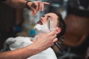 hombre con bigotes afeitados. maquinilla de afeitar en manos de peluquero especialista. un joven que se afeita a la antigua en la barbería. primer plano, imágenes de estilo retro foto