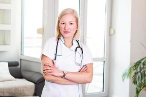 retrato de una atractiva joven doctora caucásica con bata blanca. doctora en medicina sonriente, profesional de la salud con bata de laboratorio y estetoscopio. foto