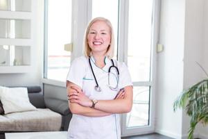 joven doctora sonriente. atractivo joven trabajador médico. doctora con los brazos cruzados. una doctora confiada posando en su oficina. primer plano de una doctora con estetoscopio foto