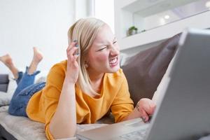 confused albino woman working from home, typing email on laptop, sitting on sofa. Laptop bugging and showing error. Software not functioning properly photo
