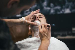 hombre con bigotes afeitados. maquinilla de afeitar en manos de peluquero especialista. un joven que se afeita a la antigua en la barbería. primer plano, imágenes de estilo retro foto