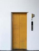 Yellow lift closed door with white wall background photo