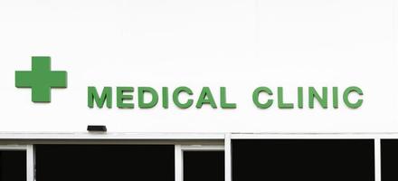 Icon green cross with message MEDICAL CLINIC on white wall building photo