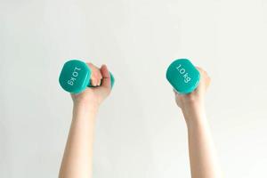 Close-up image of two hands lifting dumbbells overhead on white background. photo