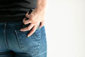 una mujer guarda una billetera corta en el bolsillo trasero de los jeans sobre un fondo blanco con espacio para copiar. foto