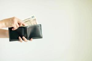 A hand is picking Japan paper money in the currency of Yen or JPY from the short wallet for payment. photo