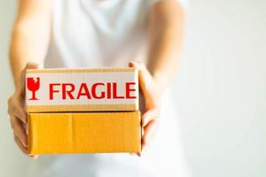 Close-up image of two hands holding and offer two parcel boxes on white background, selective focus. photo