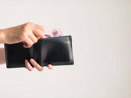 Hands holding a wallet that has Thai banknotes 500 Baht in it. photo