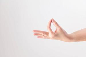 Hand supine and touching tip of thumb and forefinger together on white background, posturing like holding very small, thin and delicate object. photo