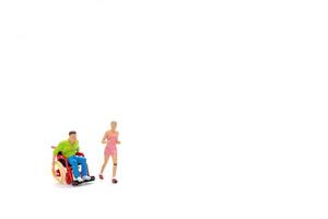 Miniature people Cheerful woman with young disabled man in wheelchair running photo