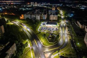 noche sobre cruce de carreteras, carretera de intersección con coches con faros en la carretera. vida nocturna en la gran ciudad. mirando hacia abajo en el tráfico foto