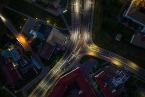 noche sobre cruce de carreteras, carretera de intersección con coches con faros en la carretera. vida nocturna en la gran ciudad. mirando hacia abajo en el tráfico foto