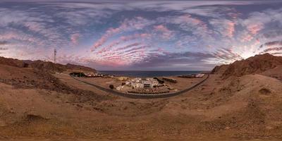 full seamless spherical hdri 360 panorama view of sunset on coast of sea high in sandy mountains with awesome clouds overlooking ancient oriental city in equirectangular projection, ready for VR AR photo