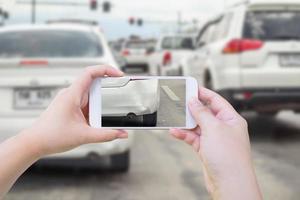 mano usando un teléfono inteligente móvil tomando una foto del daño del accidente automovilístico para el seguro