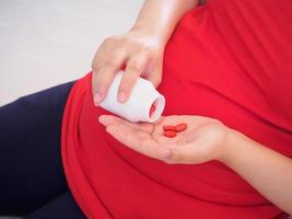 pregnant woman with vitamin pills on her hand photo