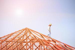 welder workers installing steel frame structure of the house roof at building construction site photo