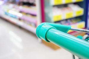 shopping cart with abstract blur supermarket discount store product shelves interior defocused background photo