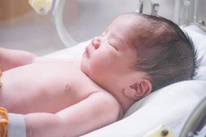 Newborn baby girl inside incubator in hospital post delivery room photo