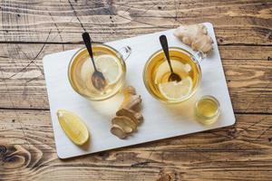 Two cups of natural herbal tea ginger lemon and honey on a wooden background. photo