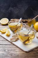 Two cups of natural herbal tea ginger lemon and honey on a wooden background. Copy space photo