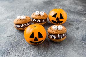 Cookies with chocolate paste in the form of monsters and pumpkin tangerines for Halloween