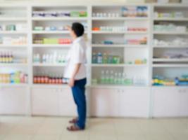 blur pharmacist taking medicine from shelf in the pharmacy photo