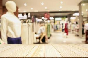 Empty wood table with woman fashionable boutique clothing store window display in shopping mall photo