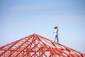 welder workers installing steel frame structure of the house roof at building construction site photo