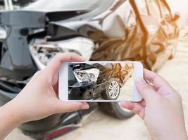 Hembra sostenga teléfono inteligente móvil fotografiando accidente automovilístico foto