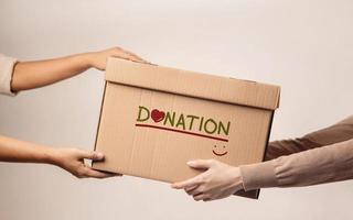 Donation Concept. The Volunteer Giving a Donate Box to the Recipient. Standing against the Walll photo