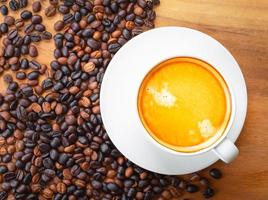 Top view of coffee cup has golden foam and mixed or blend coffee beans  on wooden backgrou photo