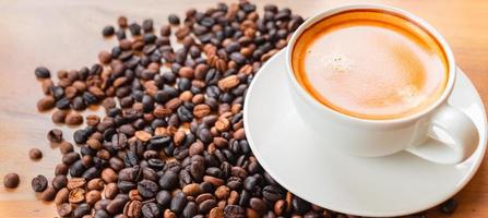 Close-up of a cup of latte with golden foam and mixed or blend coffee beans  on an old wooden floor, top view. photo