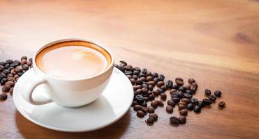 Close-up of a cup of latte with golden foam and mixed or blend coffee beans  on an old wooden floor, top view. photo