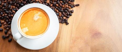 Top view of coffee cup has golden foam and mixed or blend coffee beans  on wooden backgrou photo