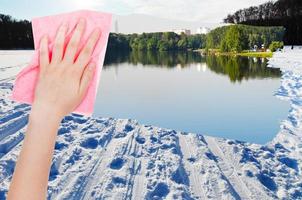 hand deletes snow field on frozen river by cloth photo