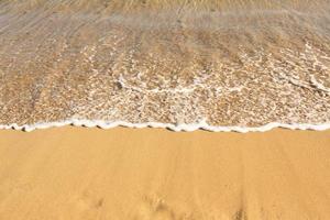 Background with golden sand on the coast of the island of Crete. Abstract surface with sand and clear sea water for text. photo