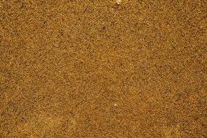 Background with golden sand on the coast of the island of Crete. Abstract surface with sand and clear sea water for text. photo