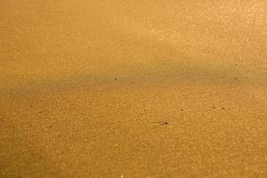 Background with golden sand on the coast of the island of Crete. Abstract surface with sand and clear sea water for text. photo