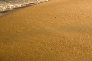 Background with golden sand on the coast of the island of Crete. Abstract surface with sand and clear sea water for text. photo