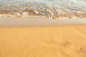 Background with golden sand on the coast of the island of Crete. Abstract surface with sand and clear sea water for text. photo