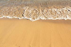 Background with golden sand on the coast of the island of Crete. Abstract surface with sand and clear sea water for text. photo