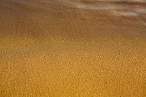 fondo con arena dorada en la costa de la isla de creta. superficie abstracta con arena y agua de mar clara para texto. foto