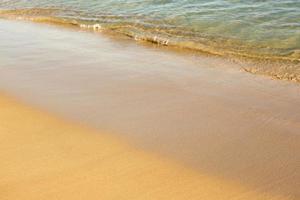 Background with golden sand on the coast of the island of Crete. Abstract surface with sand and clear sea water for text. photo