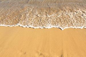 Background with golden sand on the coast of the island of Crete. Abstract surface with sand and clear sea water for text. photo