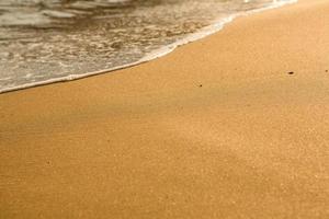 Background with golden sand on the coast of the island of Crete. Abstract surface with sand and clear sea water for text. photo